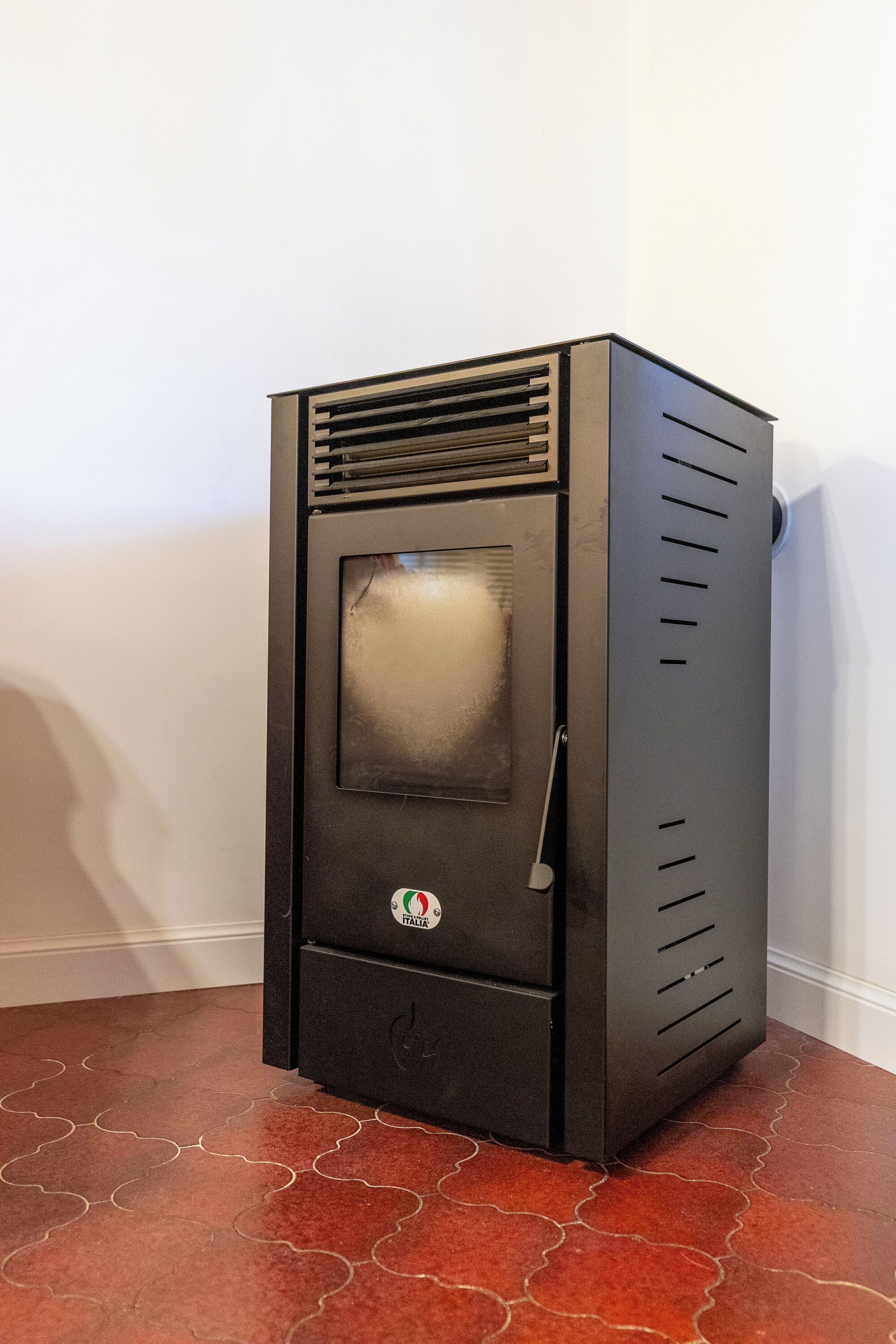 A black, stationary heater with a glass door, a control panel, and a logo on the front.