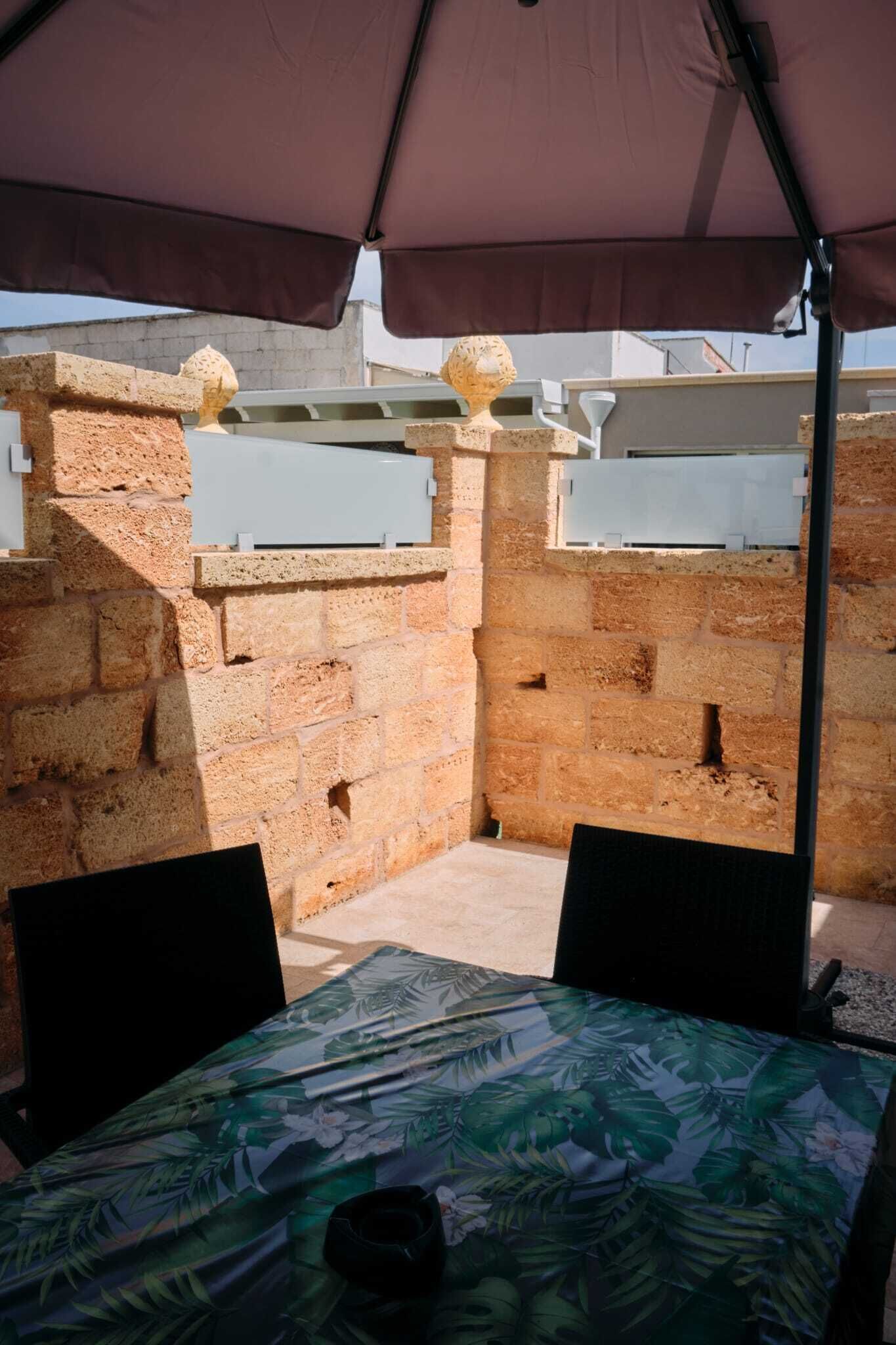 Ein überdachter Außenbereich mit Tisch und Stühlen, einer Ziegelwand und einer weißen Klimaanlage.