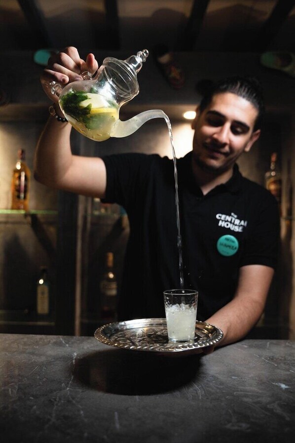 A person pouring a drink into a glass on a tray. - The Central House Marrakech Medina (Marrakech)