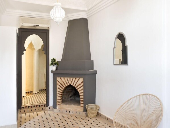 A modern interior with a fireplace, a wicker chair, and a mirror on the wall. - The Central House Marrakech Medina (Marrakech)