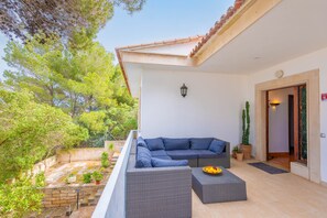 A balcony with a grey sofa, a small table with a fruit bowl, and a potted cactus. - Ca n Quiros in Mallorca (Santa Margalida)