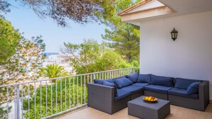 A balcony with a wicker sectional sofa, a small table with fruit, and a railing. - Ca n Quiros in Mallorca (Santa Margalida)