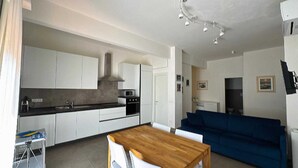 A compact living space with a kitchenette, a dining area, and a seating area. - casa homie (Lavagna)