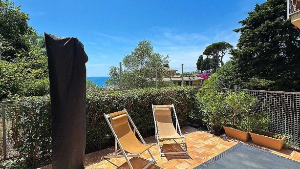 A patio with two lounge chairs, a pergola, and a view of the sea. - casa homie (Lavagna)