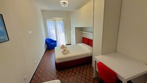 A hotel room with a bed, a desk, a chair, and a blue armchair. - casa homie (Lavagna)