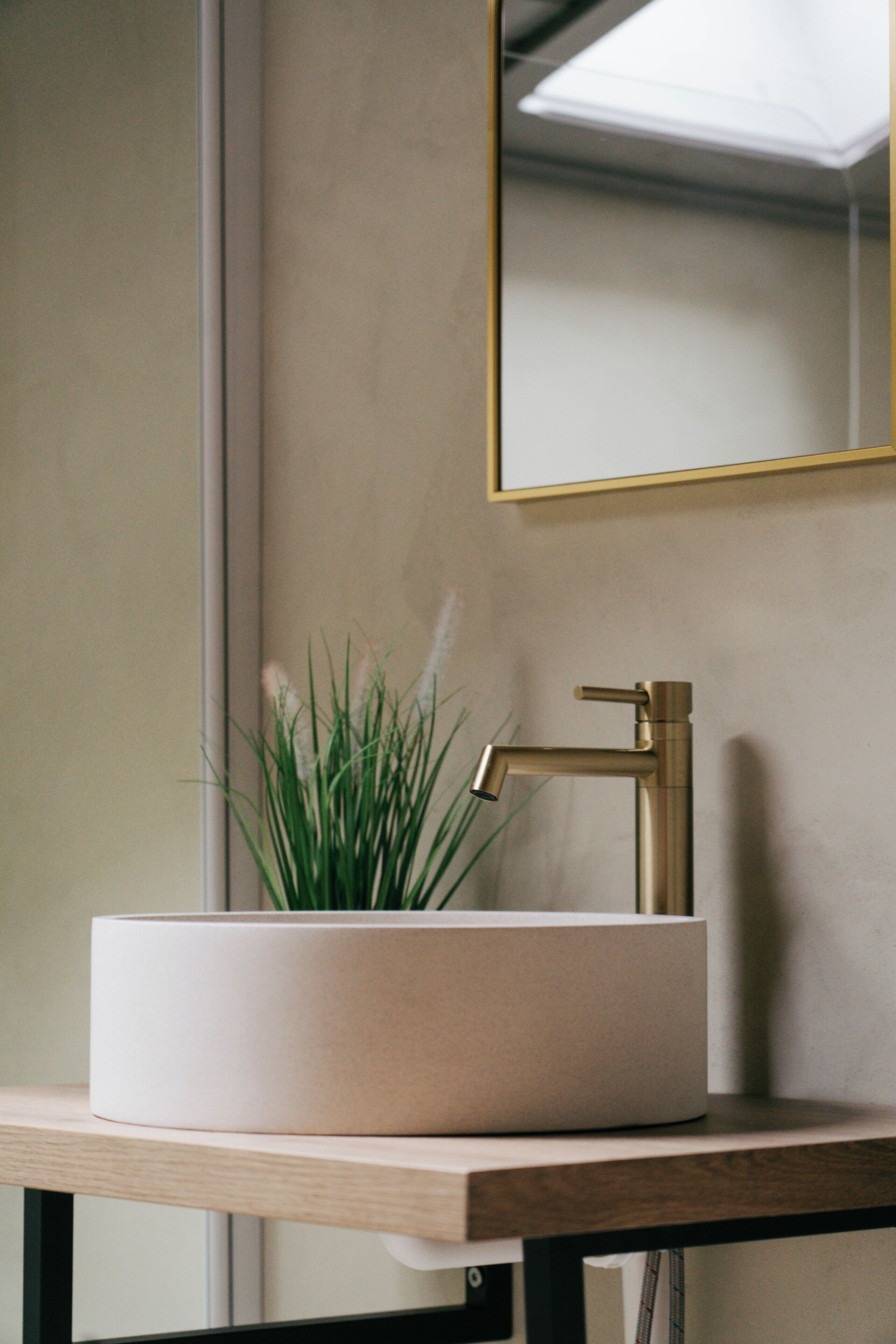 A bathroom with a white sink, a gold faucet, and a mirror with a gold frame.