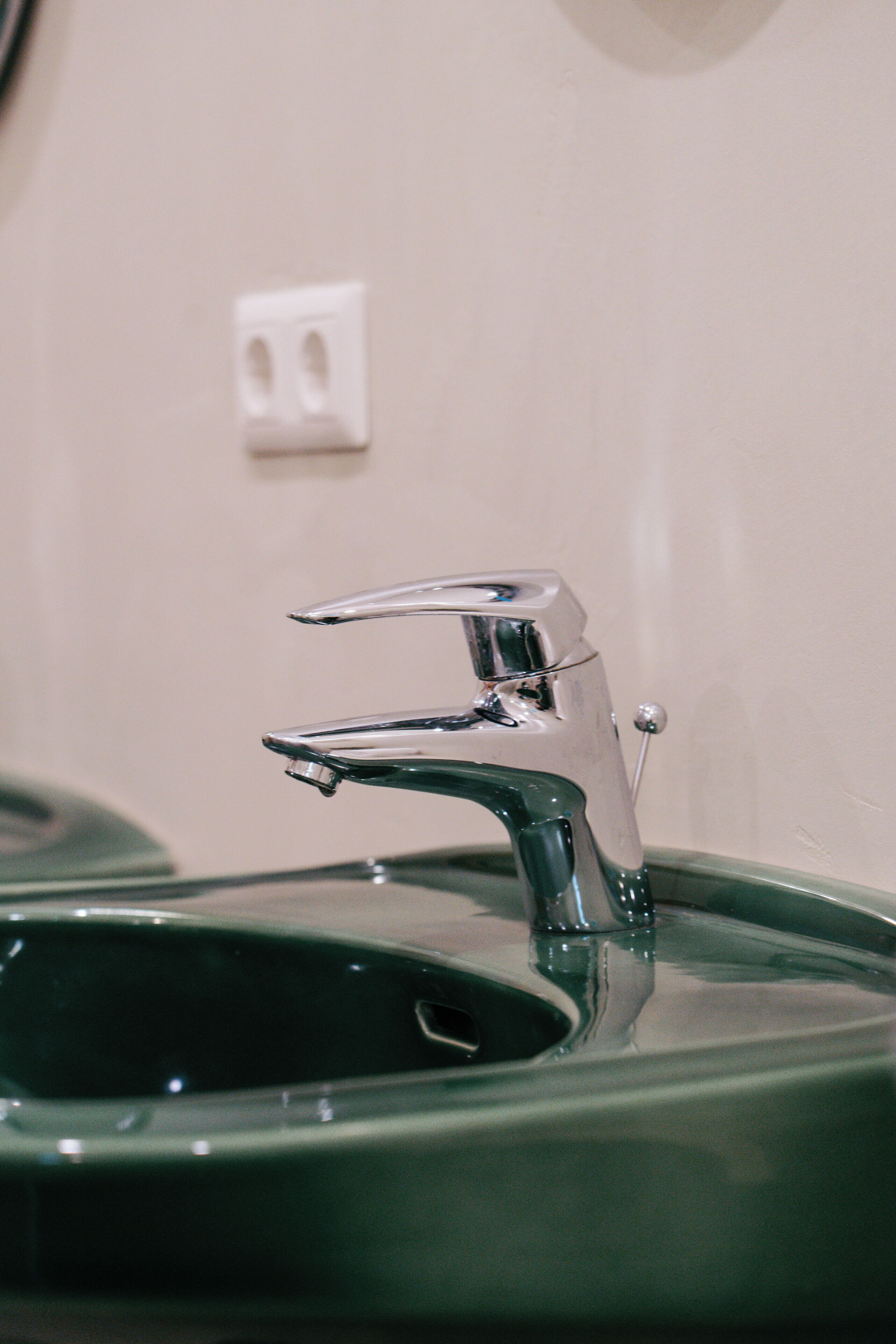 A bathroom sink with a chrome faucet and a green basin.
