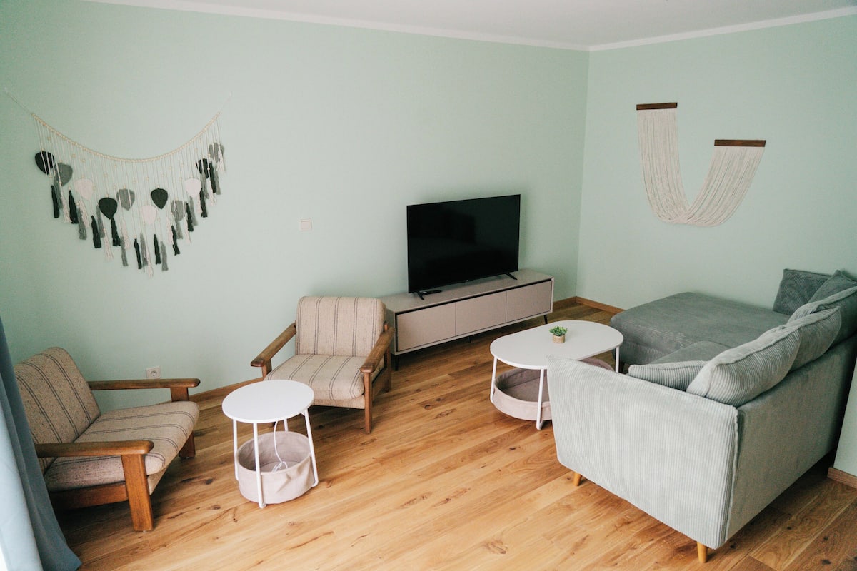 A living room with a sofa, two chairs, a TV, and a small table.