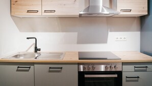 Una cocina con armarios de madera, un lavamanos de acero inoxidable, una campana extractora y un horno empotrado.