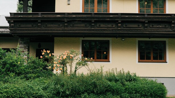 Una cabaña tradicional con techo inclinado, balcones de madera y un jardín bien cuidado.