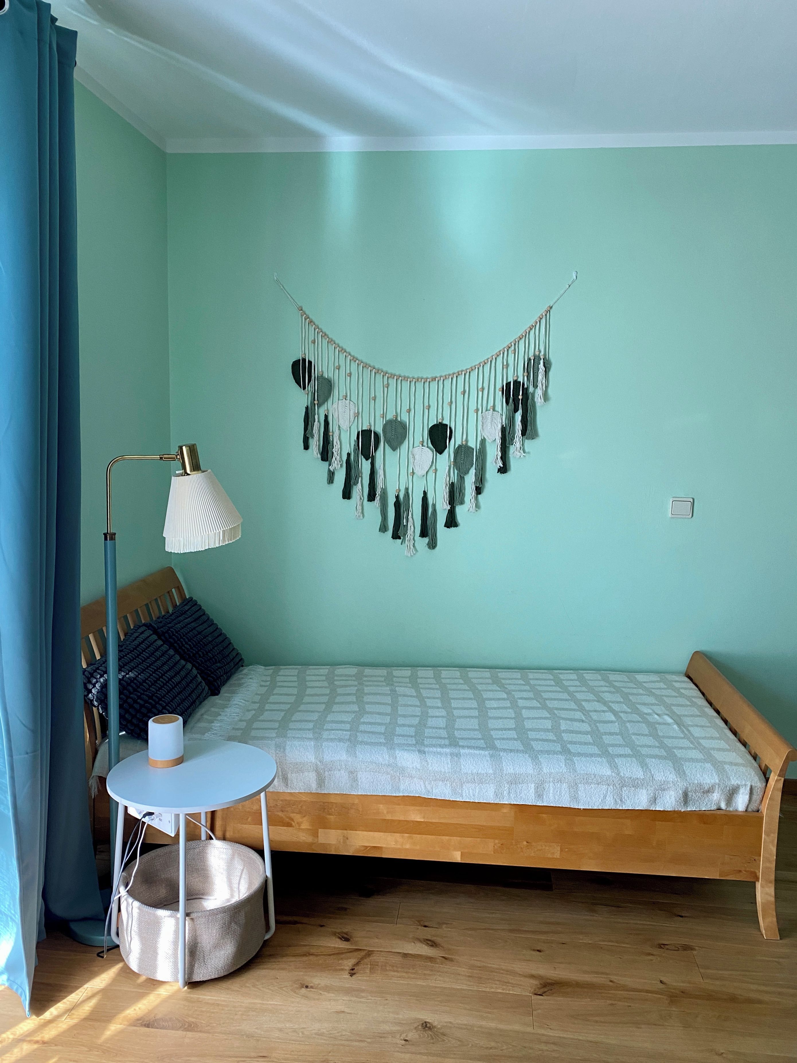 Ein Zimmer mit einem Bett, einem kleinen runden Tisch, einer Stehlampe und einer Wanddekoration.