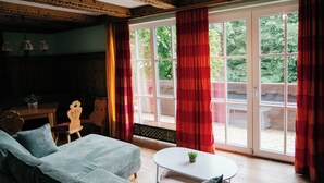 Una habitación acogedora con una cama, una mesita con una planta y una ventana con cortinas rojas.