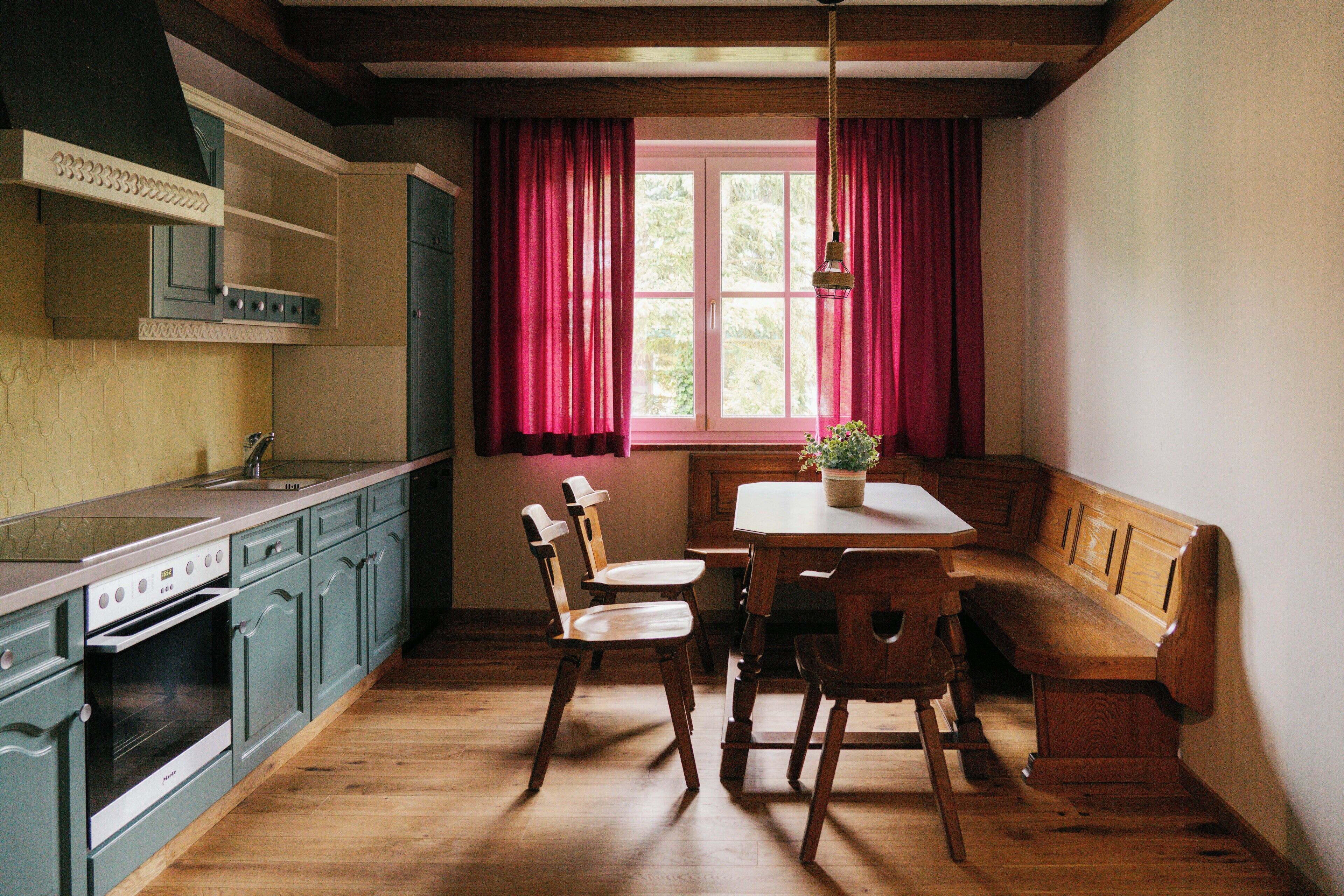 A kitchen with wooden cabinets, a dining table, and a bench.