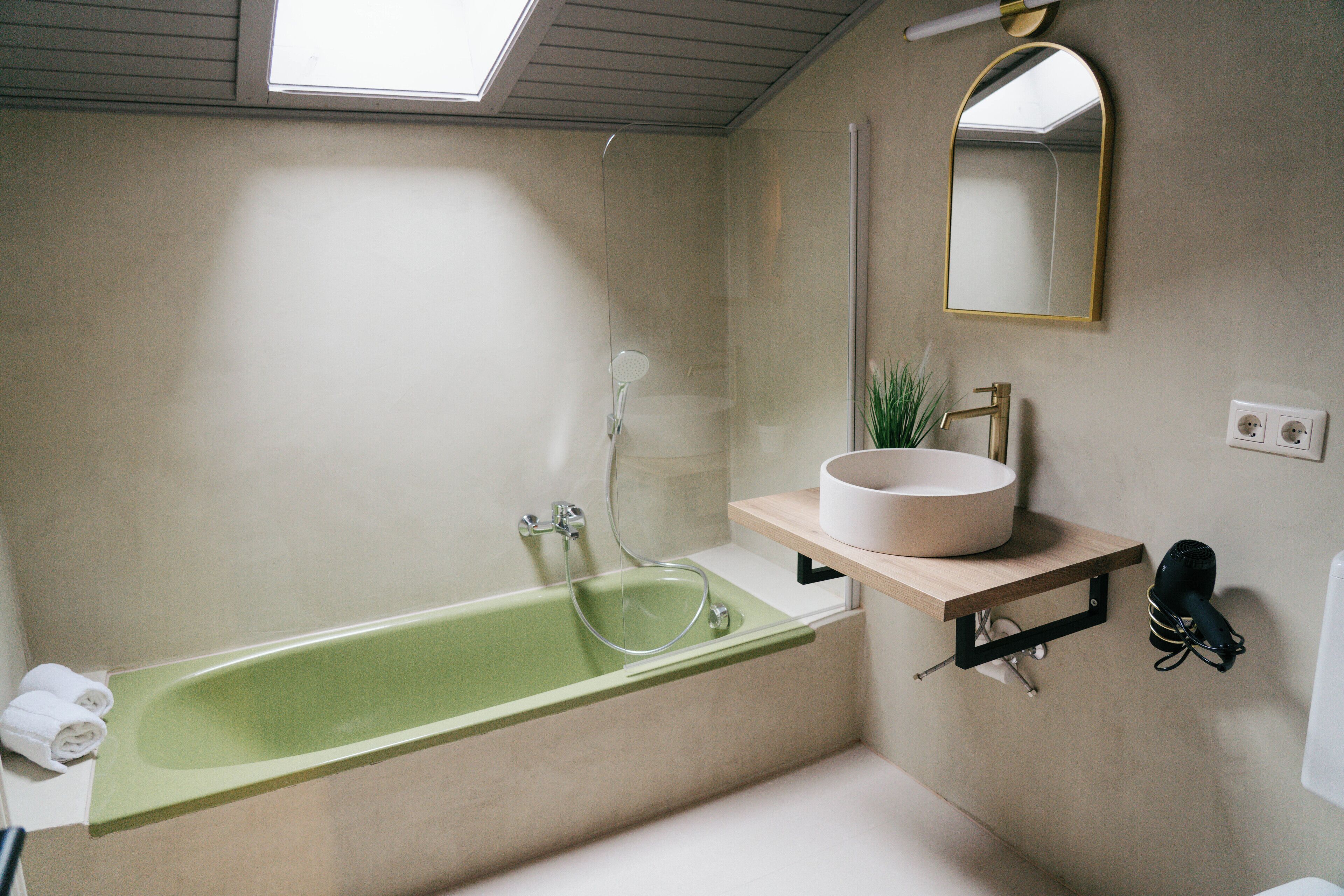 Un baño moderno con una bañera verde, un lavabo blanco y un espejo sobre el lavabo.