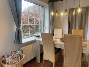 Un coin repas avec des chaises en osier, une table et une fenêtre avec des rideaux.
