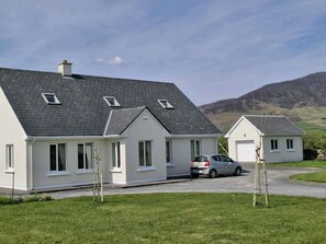 Une maison à deux étages avec une voiture garée dans l’allée.