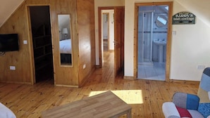 Ein Holzinnenraum mit Schlafzimmer im Zwischengeschoss, einem Badezimmer mit Dusche und einem Schild mit der Aufschrift 'Barry's Irish cottage'.