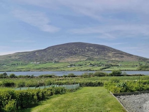 A rural landscape with a hill, fields, and a body of water.