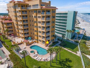 Un hôtel à plusieurs étages doté d’une piscine, d’un espace extérieur aménagé et offrant une vue sur la plage.