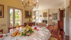 A dining room with a chandelier, dining table set for a meal, and a view of the outdoors. - Villa Lia 10, Emma Villas (Roccafluvione)