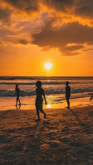 A beach scene with people walking along the shore during sunset. - Masaya Tayrona & Beach Club (Santa Marta)