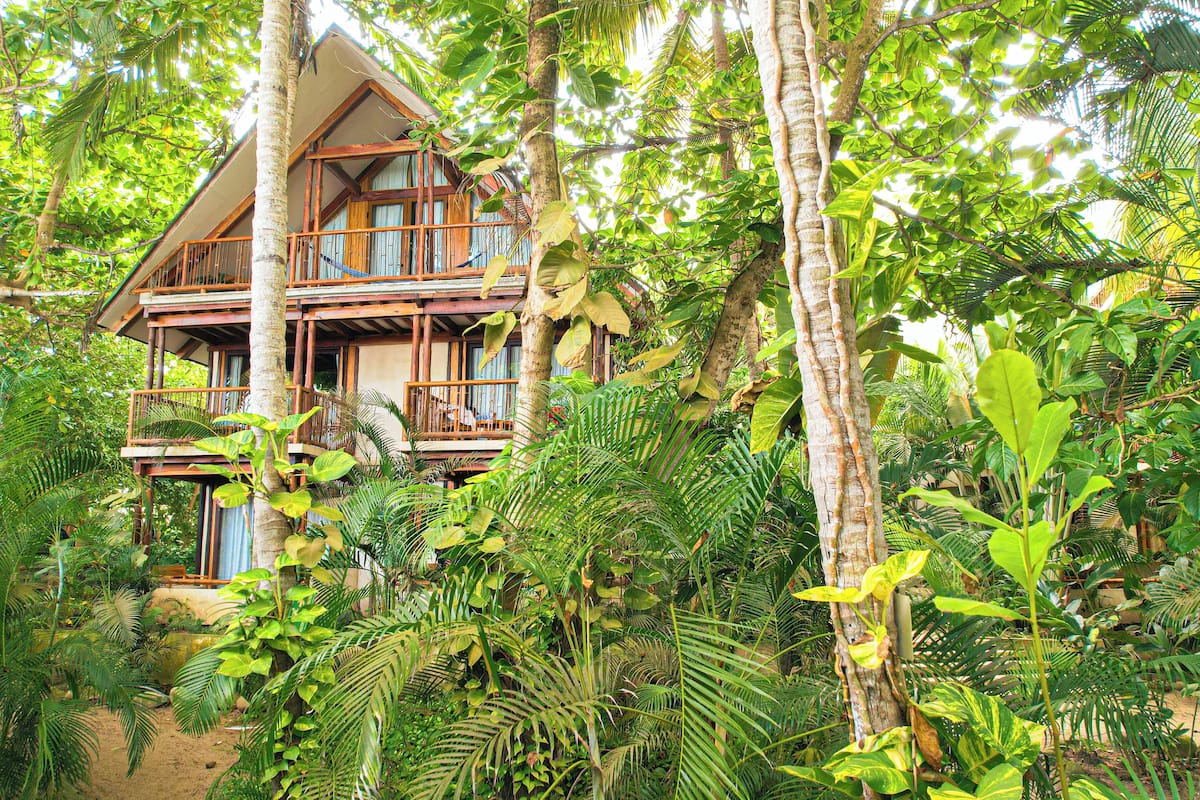 Una casa de madera de dos pisos rodeada de exuberante follaje tropical.