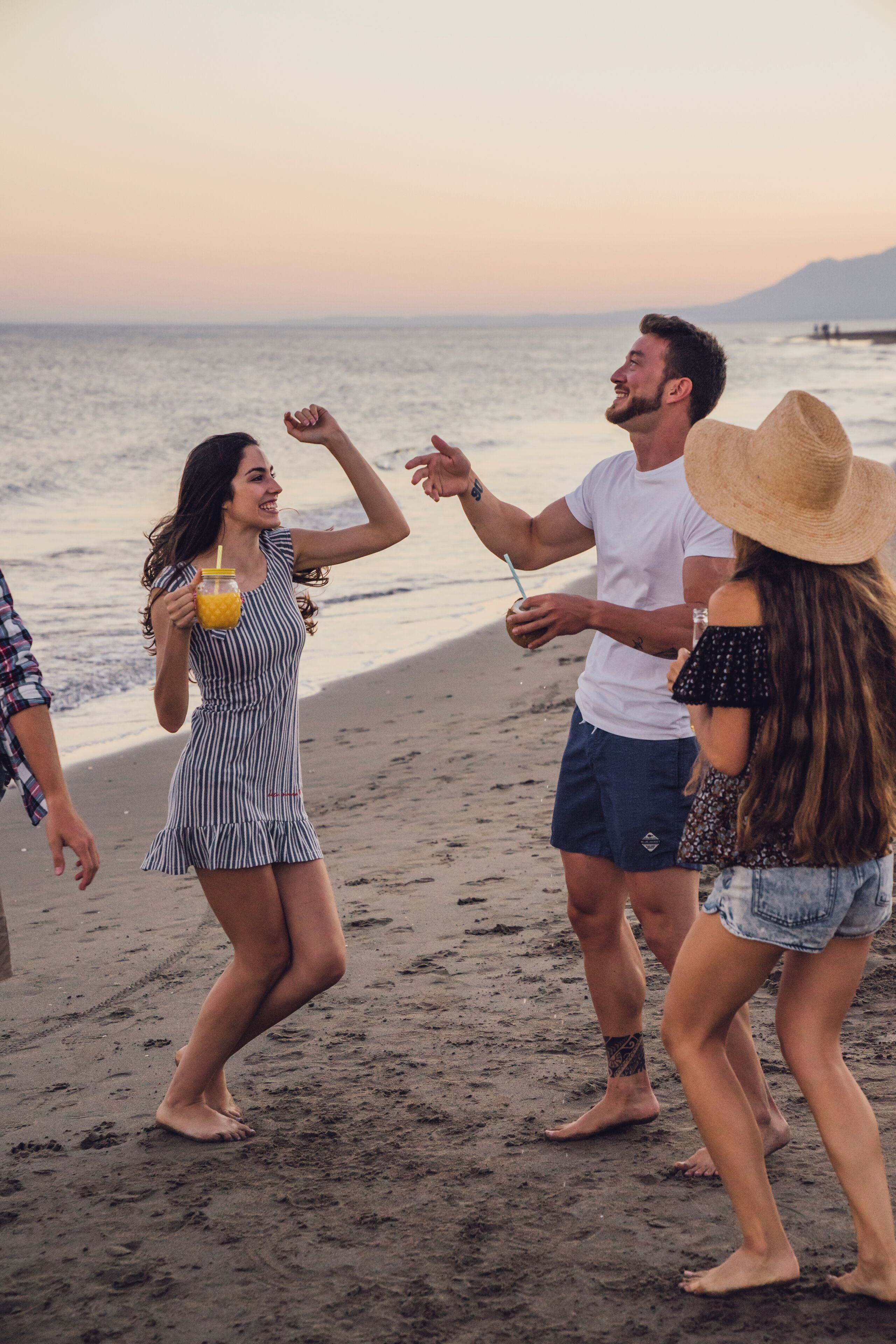 A group of people on a beach with a sunset in the background.