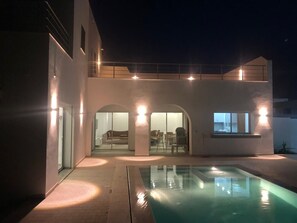 A modern house with a swimming pool, a covered patio, and a glass-enclosed living area. - Charming 4-bedroom villa with pooland  with WiFi in delightful Houmt Souk (Houmt Souk)