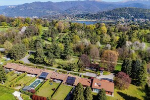 An aerial view of a residential area with houses, a swimming pool, and a lake in the background. - Country House Montorfano (Capiago Intimiano)