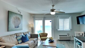 A living room with a beige sofa, a blue armchair, a wooden coffee table, a ceiling fan, and a large window with blinds. - Perdido Skye #24 by Southern Vacation Rentals (Pensacola)