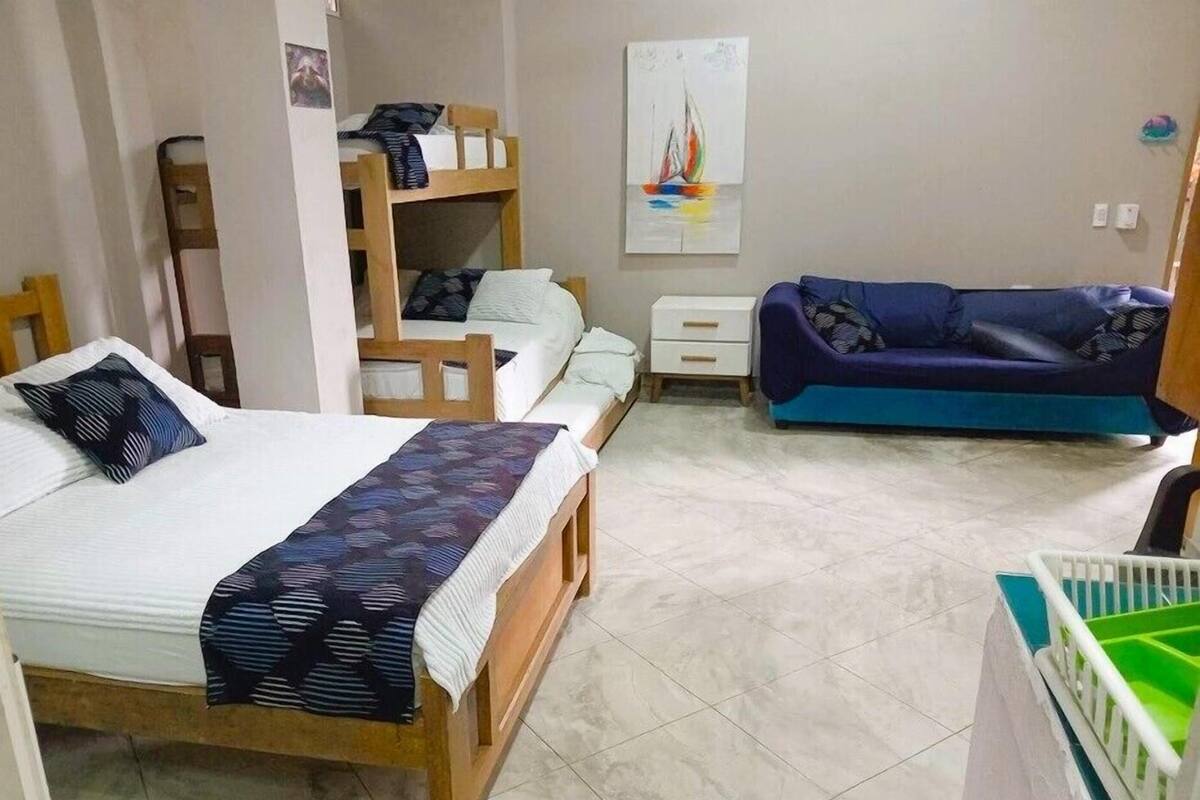 A bedroom with a bed, a bunk bed, a sofa, and a crib.