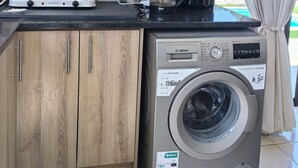 Una cocina compacta equipada con microondas, cafetera y lavadora.