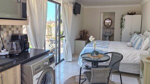 Una habitación luminosa con una cama, una mesa de comedor y una lavadora.