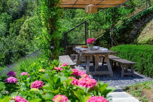 Una mesa de madera al aire libre con una lámpara colgante encima.