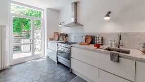 A modern kitchen with a large window, stainless steel appliances, and a marble countertop.