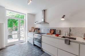 Een moderne keuken met een groot raam, roestvrijstalen apparatuur en een marmeren aanrecht.