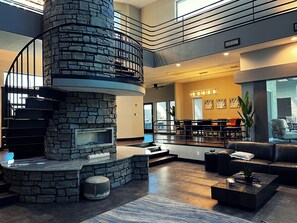Ein modernes Interieur mit Kamin aus Stein, einer Wendeltreppe und einer Sitzecke mit Ledersofas.
