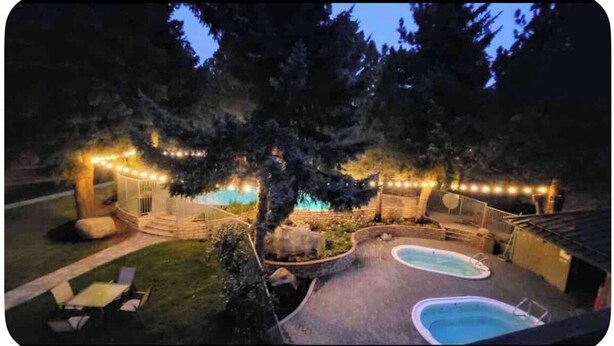 A backyard with a swimming pool, outdoor seating, and string lights. - IN TOWN CONDO WITH HOT TUB, AT SHUTTLE STOP, HAS EVERYTHING YOU NEED!! (Mammoth Lakes)
