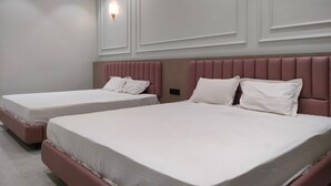 Habitación de hotel con dos camas, cada una con cabecera y ropa de cama blanca.