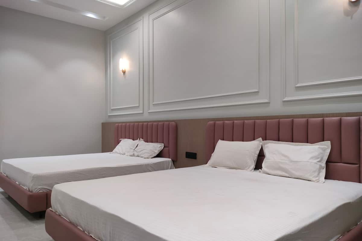 A hotel room with two beds, each with a headboard and white bedding.