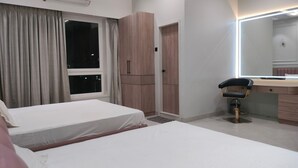 Una habitación de hotel con dos camas, un tocador con espejo y un armario.