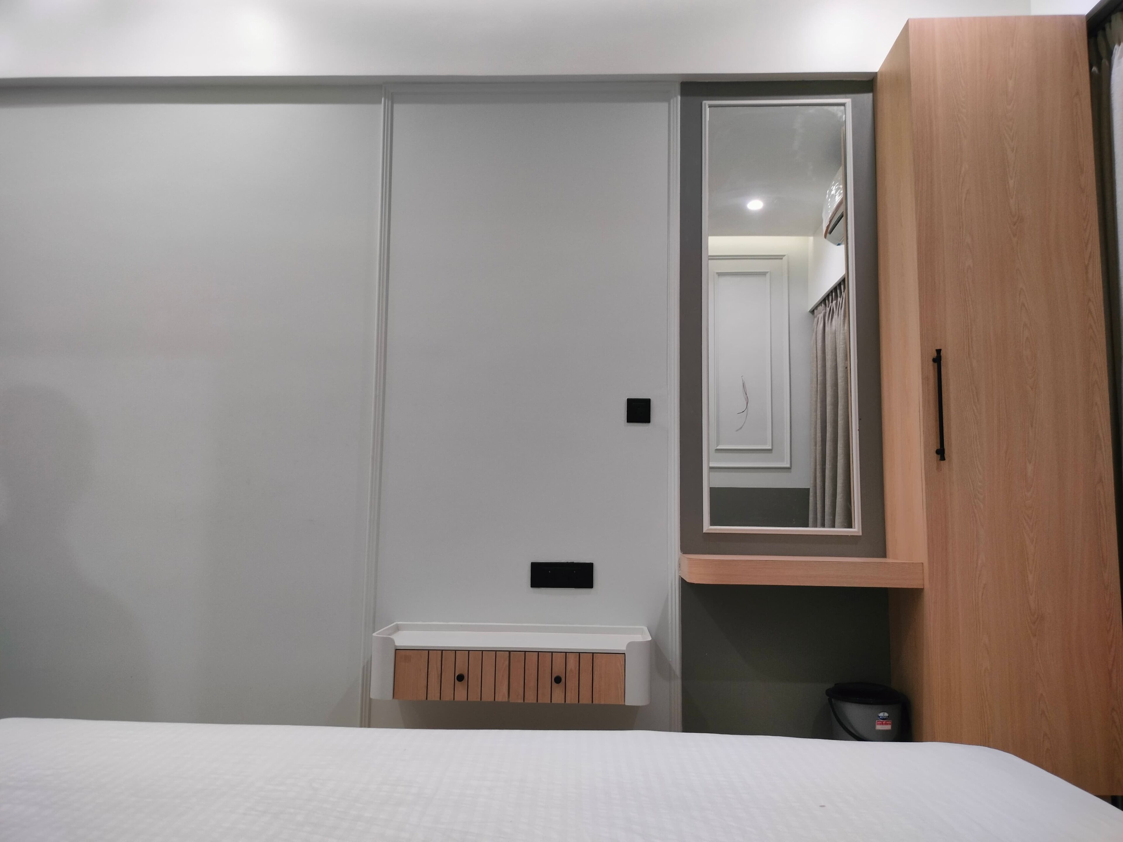 Une chambre à coucher comprenant un lit, une armoire, un miroir et un petit meuble en bois.