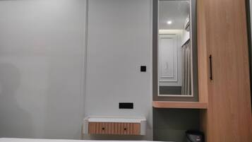Un dormitorio con cama, armario, espejo y un pequeño mueble de madera.