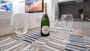A modern kitchen with white cabinets, a striped tablecloth, and a bottle of Berlucchi wine on the table. - Ortigia CLARME Cathedral Square (Siracusa)