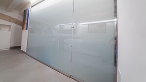 A modern room with a large sliding glass door, a flat-screen TV, and a small kitchenette area. - Ortigia CLARME Cathedral Square (Siracusa)