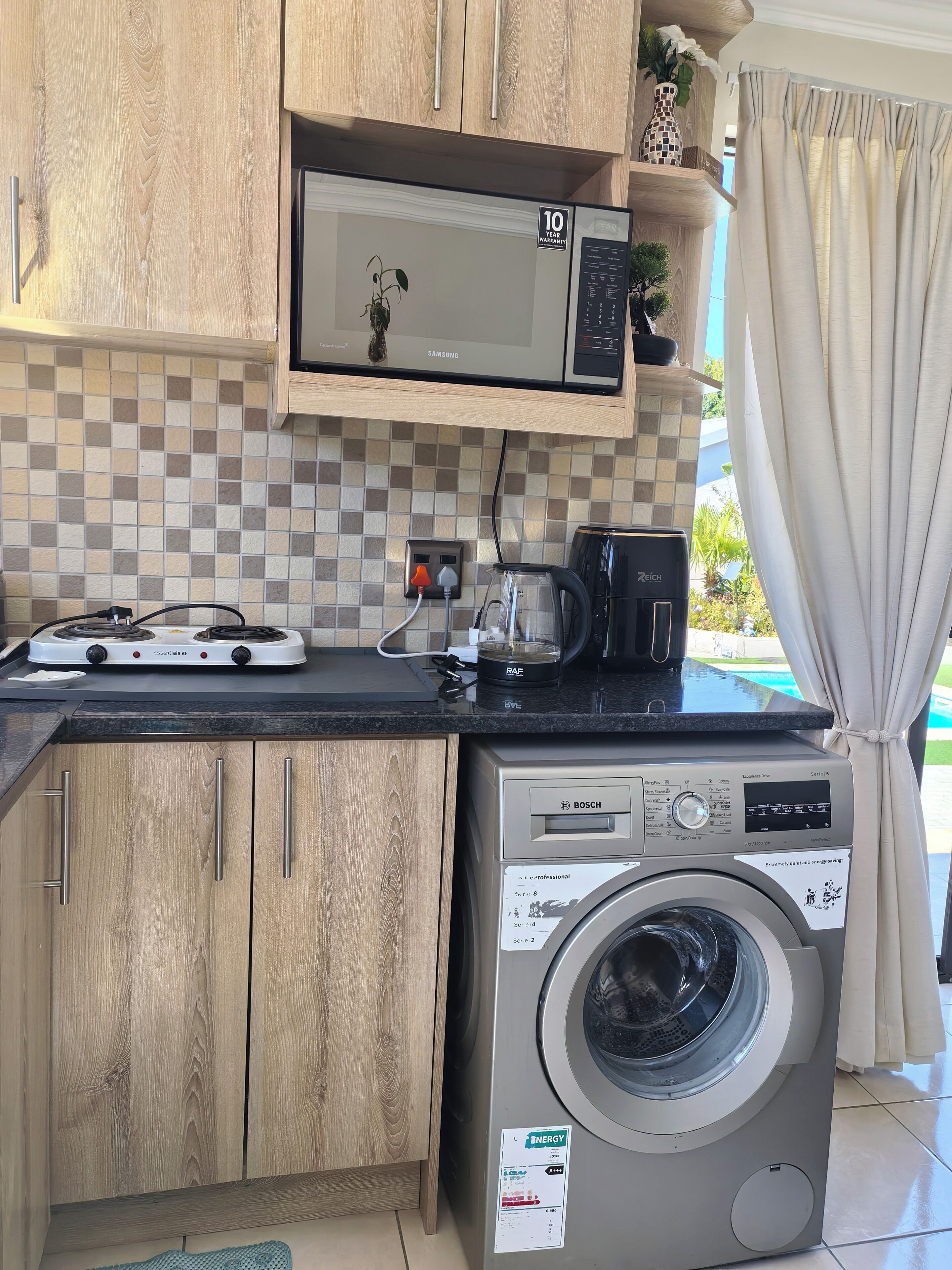 A compact kitchen with a microwave, coffee maker, and washing machine.
