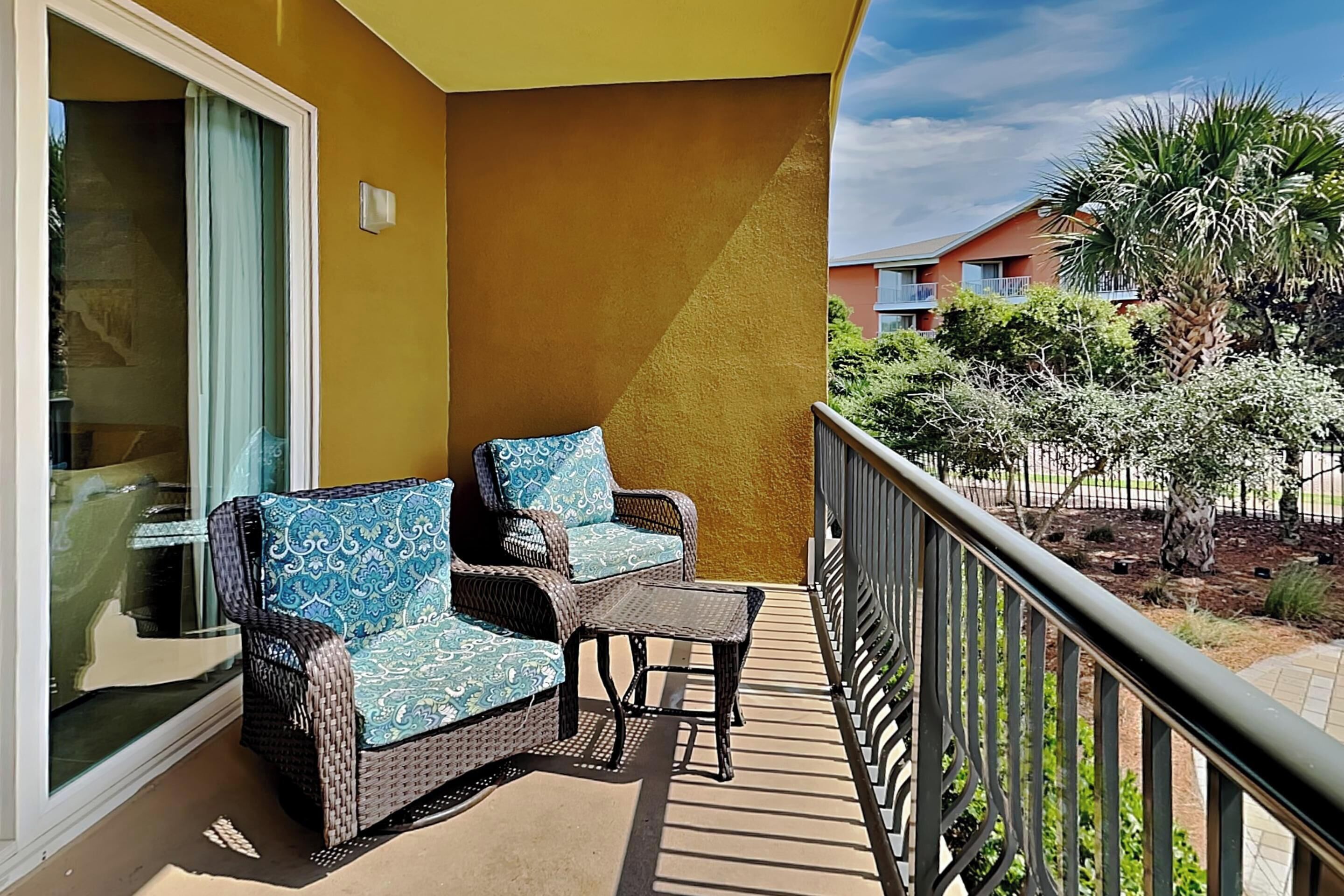 Een balkon met rieten meubilair en uitzicht op een woonwijk.