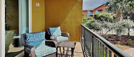 Een balkon met rieten meubilair en uitzicht op een woonwijk.