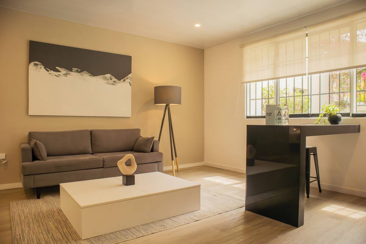 Una sala de estar moderna con un sofá, una mesa de centro, una lámpara de pie y un cuadro en la pared.