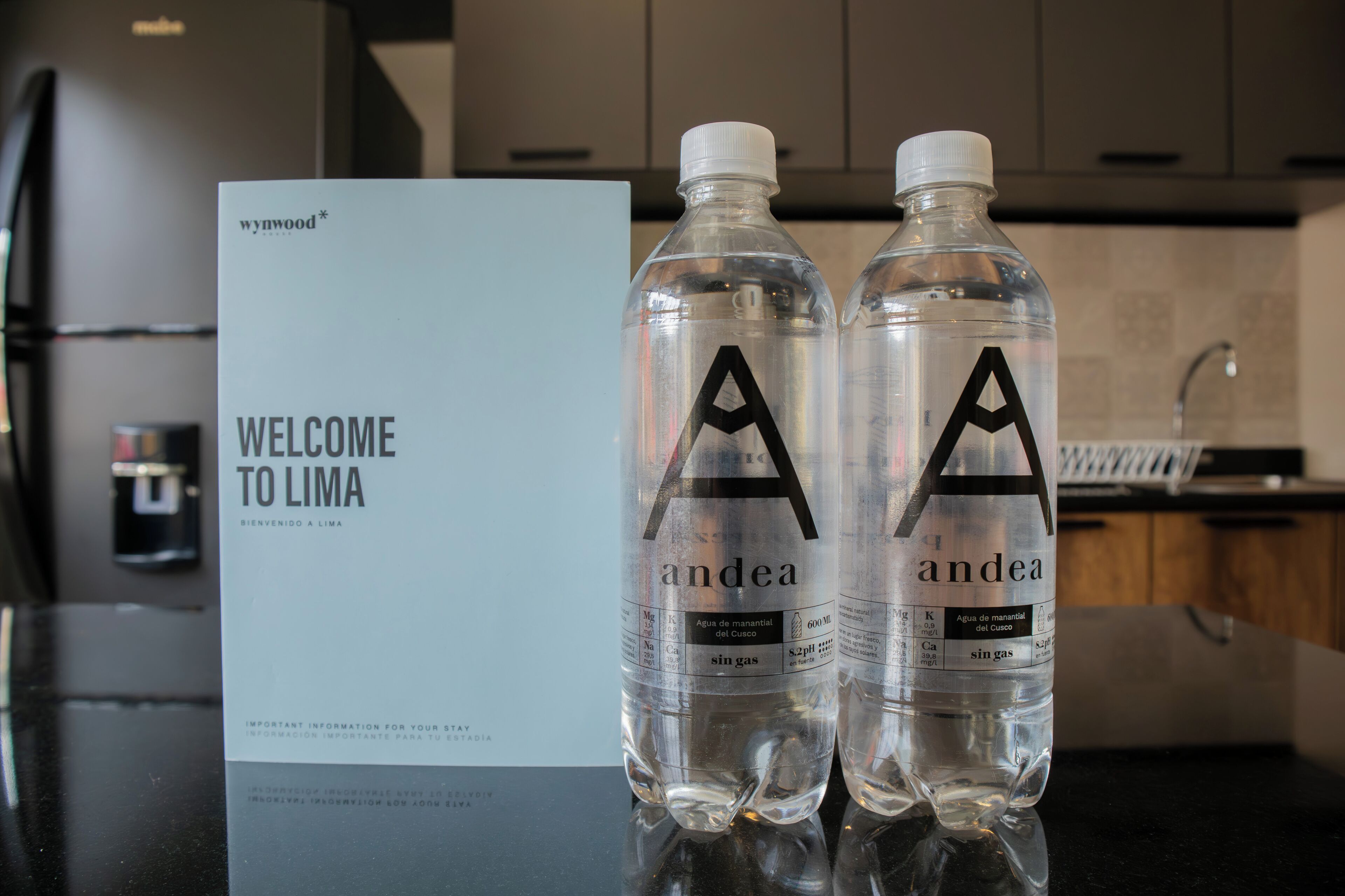 Two bottles of water with the label 'andea' and a welcome sign for 'Lima' in the background.